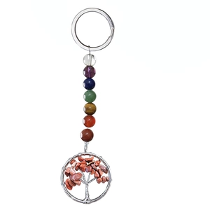 Detail of life tree keychain with 7 chakra beads and red stone chips on white background