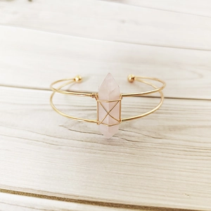Detail of handmade gold wire-wrapped cuff bracelet featuring a rose quartz hexagonal stone
