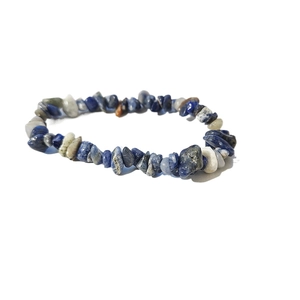 Dettaglio macro di perle in pietra naturale blu e bianca su un bracciale elastico