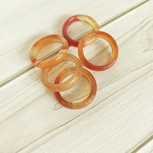 Macro detail of five natural carnelian agate rings with polished textures on wood