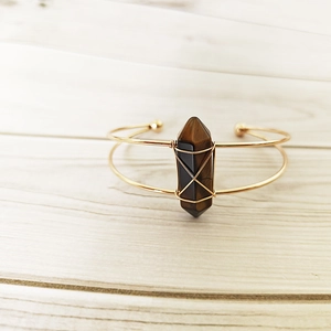 Detail of tiger eye crystal hex pillar wrapped in gold wire on a double-line open bangle