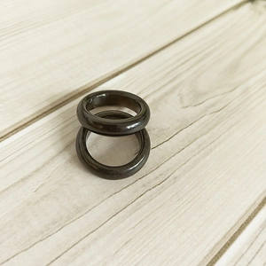 Macro view of two 6mm wide black natural agate gemstone rings on a textured wooden background