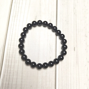 Macro detail of polished 8mm black agate stone beads on a minimalist elastic bracelet