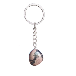 Gros plan d'un porte-clés en pierre naturelle rose polie avec texture marbrée noire