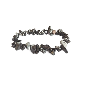 Dettaglio macro di perle irregolari in ossidiana naturale su un bracciale elastico