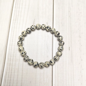 Macro detail of 8mm Dalmatian Jasper beaded bracelet showing natural black spotted texture