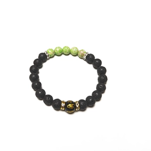 Lava stone bead bracelet with green marble accents and golden mantra charm on white background