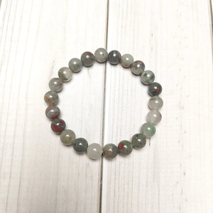 Detailed view of 8mm natural bloodstone beaded stretch bracelet on light wood surface