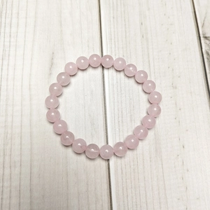 Detailed top view of 8mm pink quartz beads bracelet on a minimalist wood background