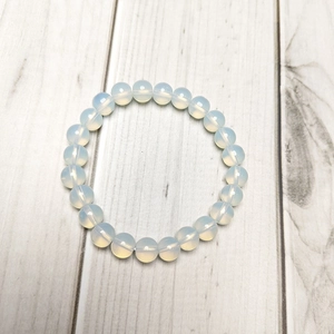 Macro shot of 8mm milky white opal beads bracelet with translucent texture on wood background