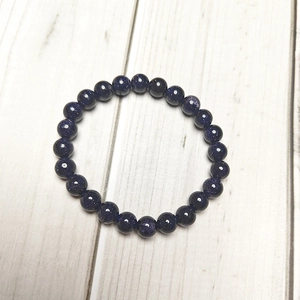 Close-up of 8mm blue sand stone beaded bracelet with starry glitter on wood background