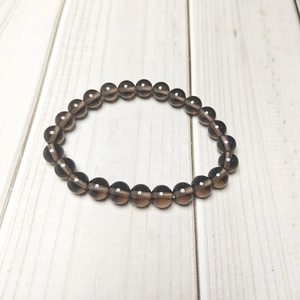 Close-up of translucent dark brown agate stone beads on a white wooden background