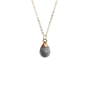 Detailed view of gray teardrop stone pendant with a delicate gold chain necklace