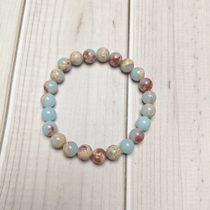 8mm natural stone beaded stretch bracelet with blue and earthy marble patterns on wood