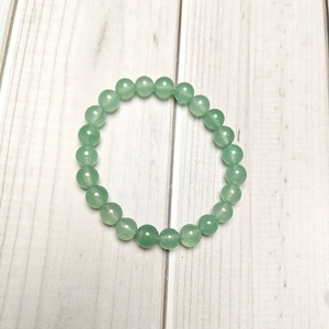 Detailed view of 8mm green aventurine beaded elastic bracelet on white wood texture