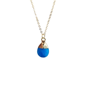 Detailed close-up of a faceted water-drop blue crystal pendant on a gold chain necklace