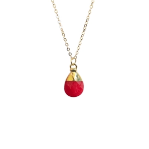 Macro detail of teardrop faceted red crystal pendant with gold plating on a fine chain