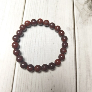 Macro shot of 8mm deep red natural stone beads with smooth texture on wood background