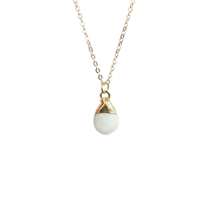 Macro detail of white quartz crystal droplet pendant with golden electroplated edges