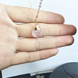 Detailed view of teardrop rose quartz pendant with gold plating on a fine chain