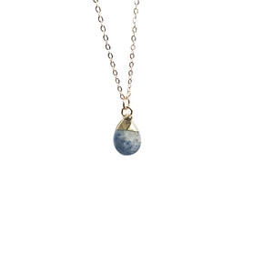 Macro detail of teardrop blue natural stone necklace with gold-plated metal edging