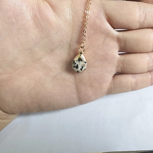 Detail of dalmatian jasper teardrop pendant with gold metal clasp on thin chain