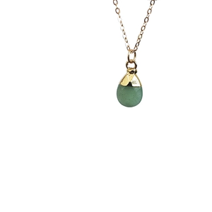 Detailed close-up of a teardrop-shaped green gemstone pendant with gold metal edging