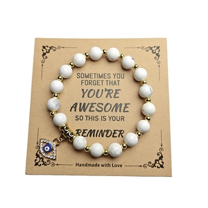Nahaufnahme von weißem Marmor-Armband mit goldenem Evil Eye Anhänger auf Karte