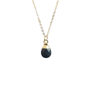 Detailed view of faceted teardrop-shaped dark gemstone pendant with golden link chain