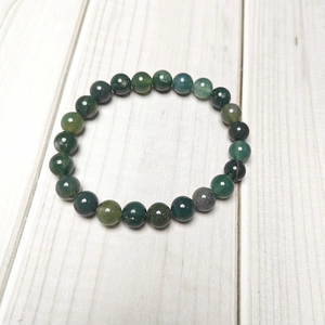 Close-up of 8mm green moss agate stone beads bracelet on a natural wood surface