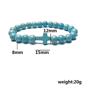 Elastic beaded bracelet with turquoise stones and cross charm displayed on white background