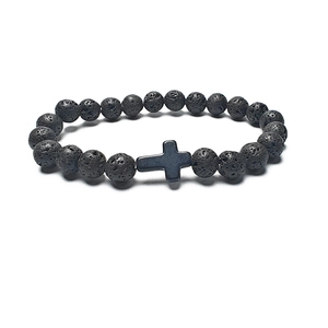 Detailed view of porous black lava rock beads and a matte black cross charm on a bracelet