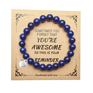 Detail of 8mm blue stone beaded bracelet with heart charm on a kraft paper gift card