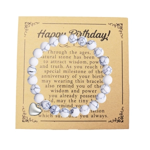 Detalle de pulsera de cuentas de mármol blanco con colgante de corazón y tarjeta de regalo