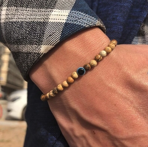 Detail van kralenarmband met tijgeroog natuursteen en een blauwe boze oog bedel