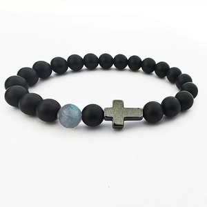 Close-up of matte black beaded bracelet with moonstone accent and metal cross charm