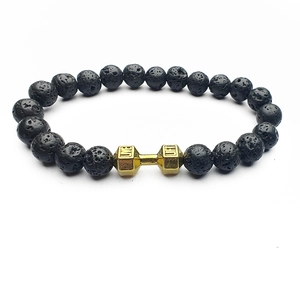 Detailed macro of black lava rock beads and golden dumbbell charm with engraved text