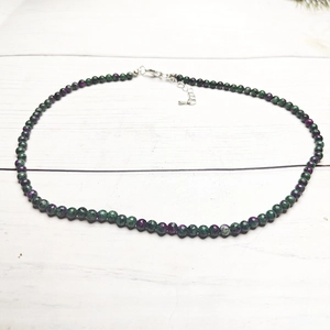 Detail view of 4mm colorful tourmaline beaded necklace with silver lobster clasp on wood