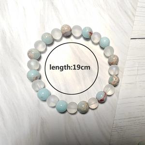 Pulsera de cuentas de piedra natural azul claro de 19 cm sobre fondo de madera blanca
