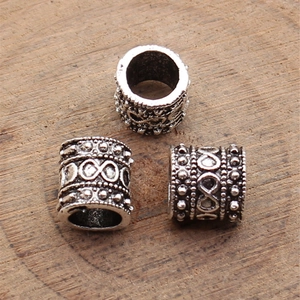 Three antique silver spacer beads with infinity relief pattern on natural wood background