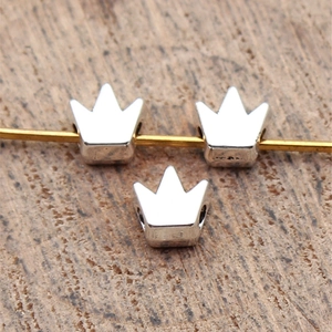Zinc alloy crown beads in vintage silver finish on a rustic wooden background