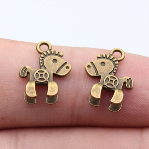 Vintage bronze horse pendant with coin pattern held on finger for scale