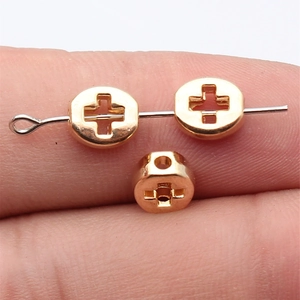 Goldene hohle Kreuz-Ovalperlen für DIY-Schmuck, zur Maßstabsdarstellung auf dem Finger