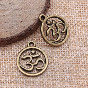 Retro bronze OM charm pendants for DIY jewelry making on a natural wood and burlap base