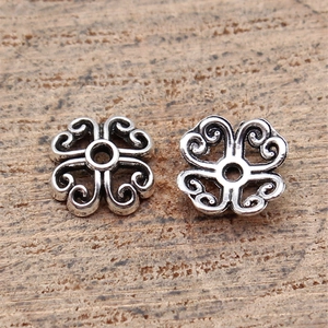 Retro clover-shaped silver flower spacers for DIY jewelry making on wooden background