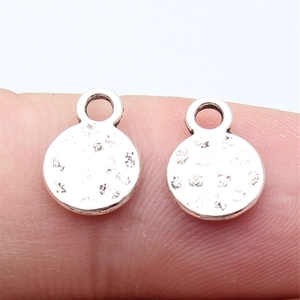 Hammered silver round metal charms on finger showing size and textured detail