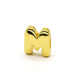 Close-up of polished gold letter M bead with smooth mirror finish for DIY jewelry