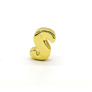 Macro view of gold plated metal letter S bead charm with smooth polished finish