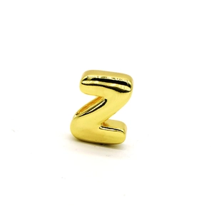Detailed macro view of a glossy gold metal letter Z bead for custom jewelry making