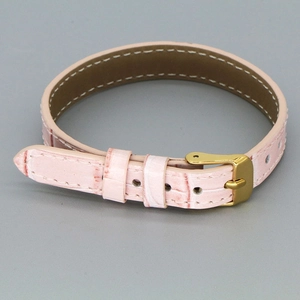 Detailed view of pink crocodile-embossed leather strap with golden buckle and white stitching
